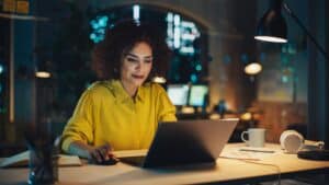 Femme travaillant tard sur ordinateur en bureau moderne.