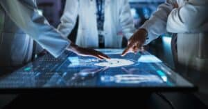 Médecins analysant IRM cérébrale sur écran tactile.