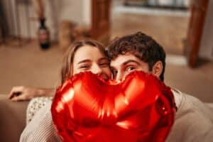 Couple tenant un ballon cœur rouge, souriants